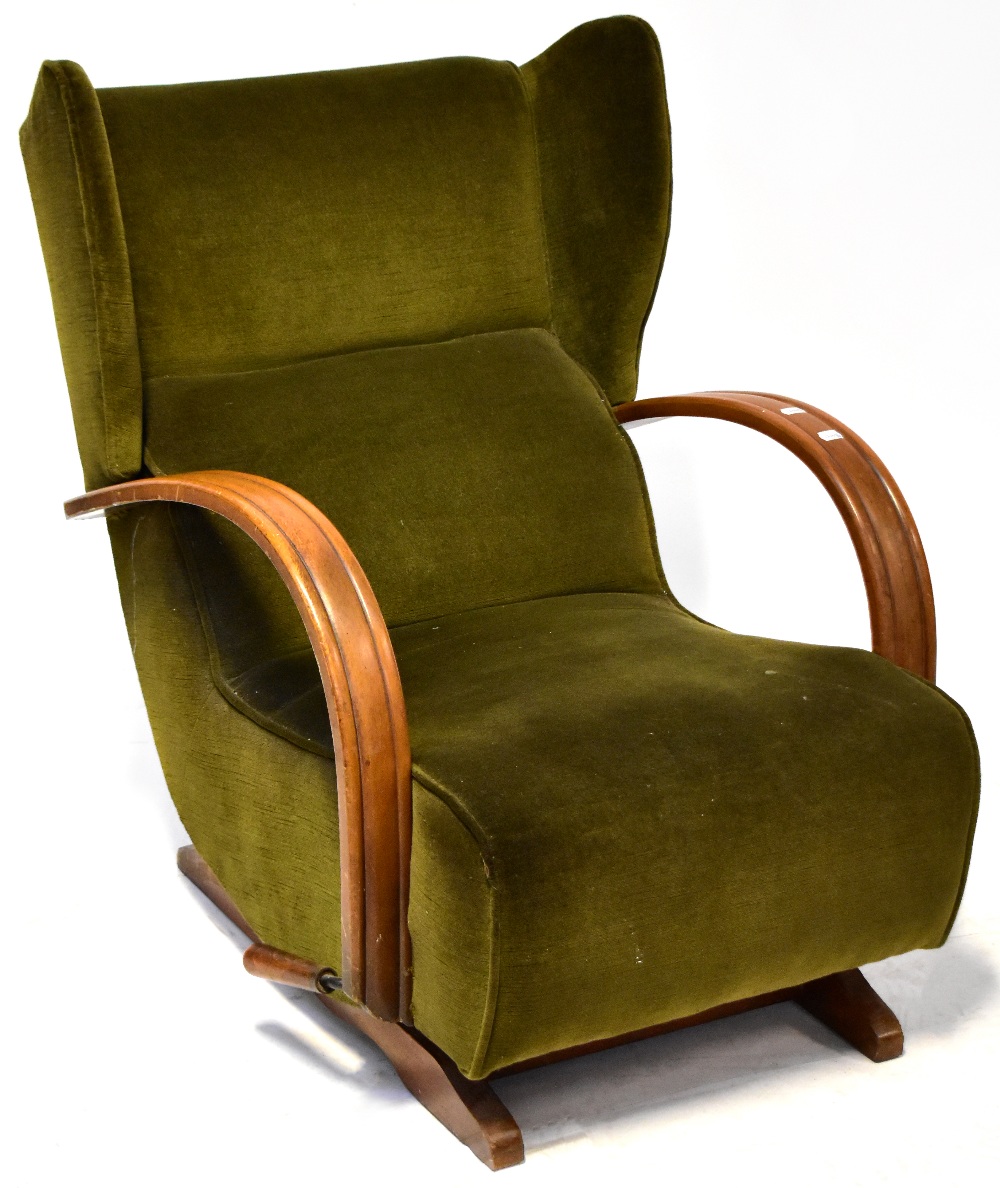 An Art Deco walnut framed wing back rocking lounge chair upholstered in green velour.