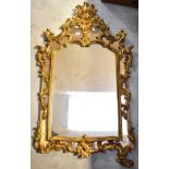 A Rococo-style wall-hanging gilt mirror, with an arched top tapering rectangular plate,