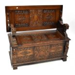 A late 19th/early 20th century oak monks' bench with three panels to the back and carved top rail,
