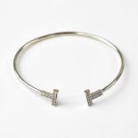 TIFFANY & CO; an 18ct white gold torque bangle, the T-shaped ends each set with nine diamonds,