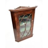 A 19th century mahogany glazed wall-hanging corner cupboard, with astragal oval motif to the door,