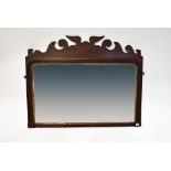 A 19th century mahogany wall-hanging mirror with shaped frieze of scrolls and wings,