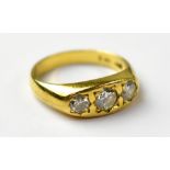 An 18ct gold ring set with three graduated diamonds within engraved mounts, size P1/2, stamped 750,
