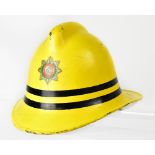 A vintage Merseyside Fire Brigade yellow helmet with printed badge to the front,