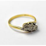 An 18ct gold three-stone diamond, with three small illusion set diamonds in possibly platinum,