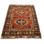 An Eastern wool woven carpet, deep rust ground with central medallions of apricot,
