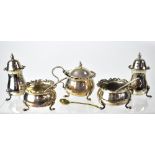 A cased George V hallmarked silver cruet set of squat form with piecrust Rococo-style scroll