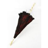 A Victorian parasol of red silk with black lace overlay,