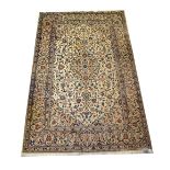 A large modern beige Kashan rug with cascading panels of floral patterns within a wide floral