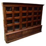 An early 20th century oak shop display/haberdashery cabinet with three banks of four shelved