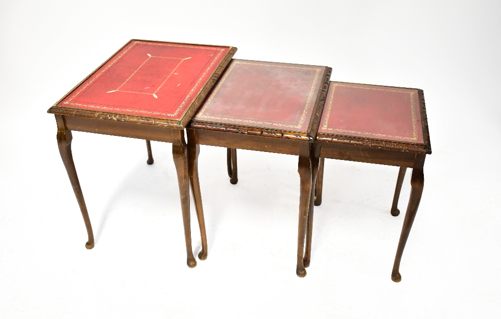 A walnut nest of three tables, with gilt tooled red leather lined tops,