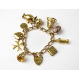 A vintage 9ct rose gold charm bracelet with ten charms, to include a silver gilt Masonic orb,