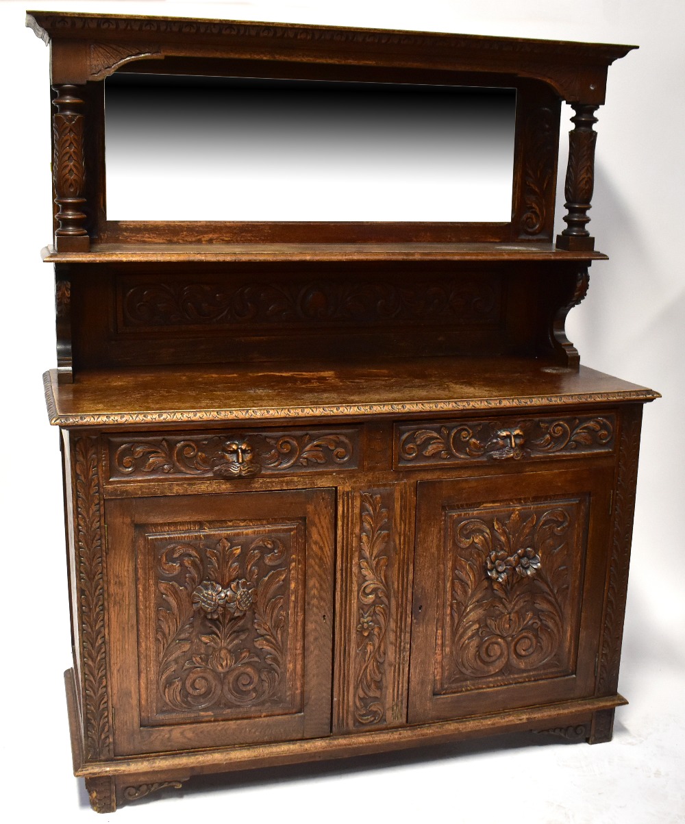 A Victorian carved oak mirror back sideboard, the carved shaped pediment with scrolls and feathers,