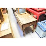 A 19th century rustic pine kitchen table with short plank drop flaps and side cutlery drawer,