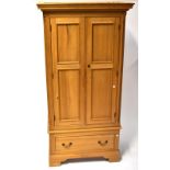 A pine single wardrobe with dentil carved cornice above a pair of panelled doors with hanging rail