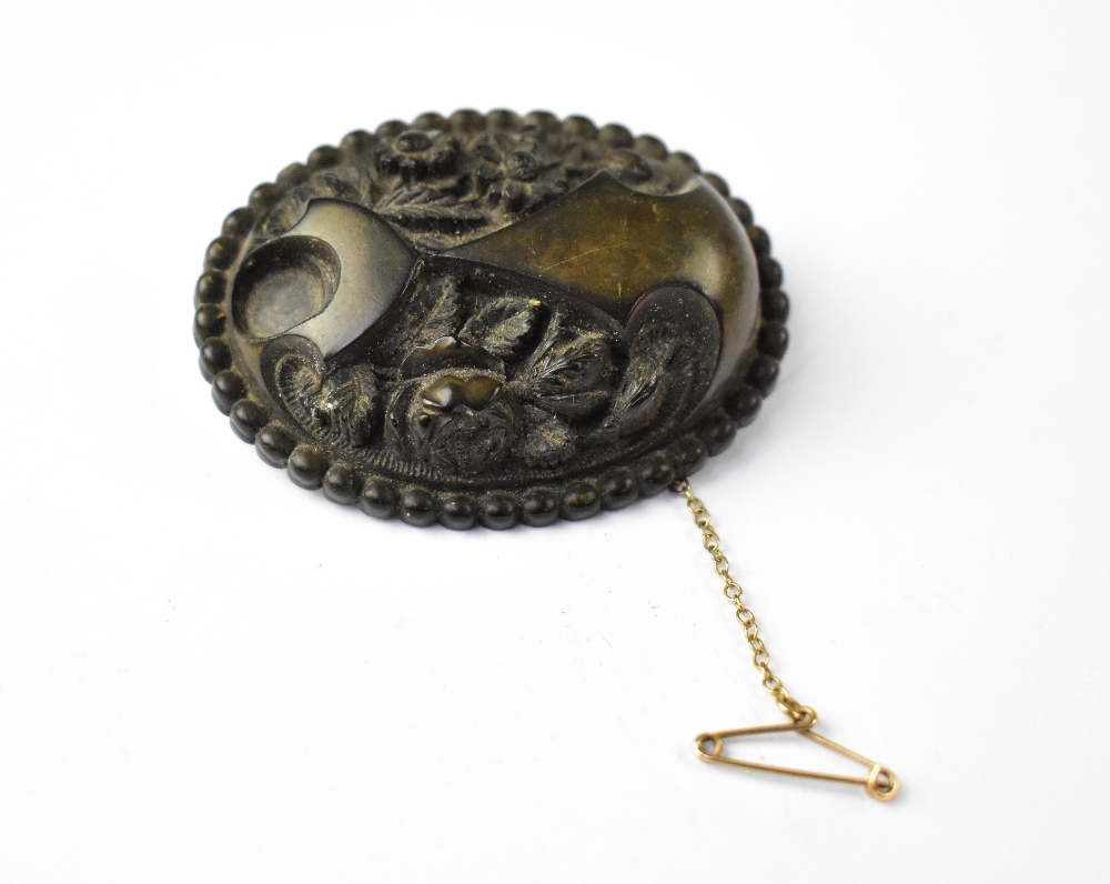 A relief carved bog oak oval brooch carved with flowers within a border,