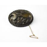 A relief carved bog oak oval brooch carved with flowers within a border,
