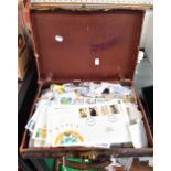 A small brown vintage suitcase containing a quantity of loose stamps, world stamps, European stamps,