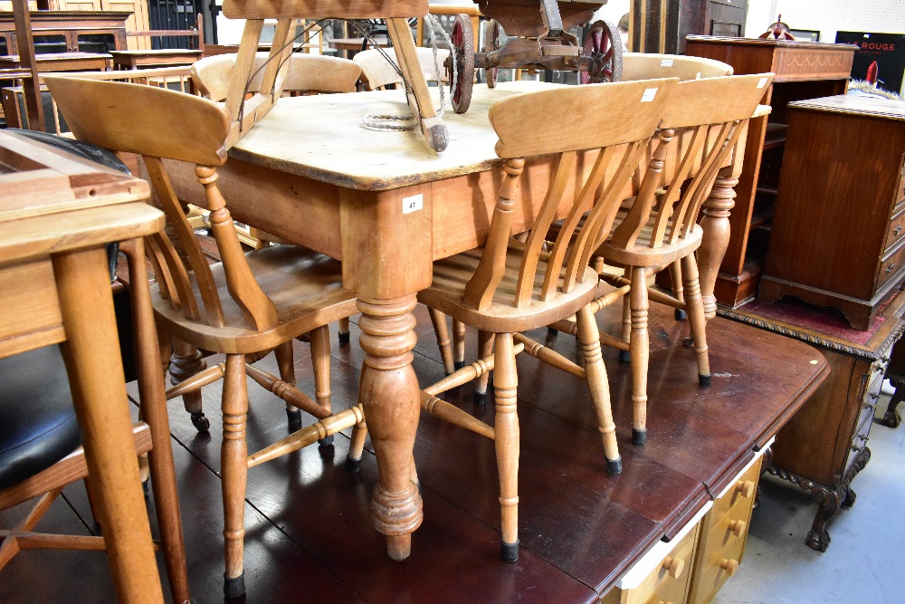 A stripped pine kitchen table of plank top construction, with broad frieze and turned supports,