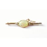 A yellow metal bar brooch set with central opal flanked by two diamonds, with safety chain.