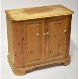 A pine bow fronted cupboard with a paid of panelled doors on plinth base, 84 x 90 x 45cm.