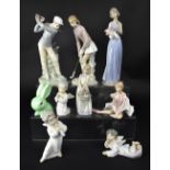 LLADRÓ; a pair of male and female golfing figures, a group of three baby angels, one reclining,