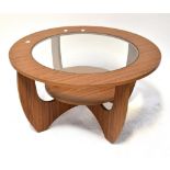 A retro circular glass topped coffee table with shaped supports united by a circular undertier,