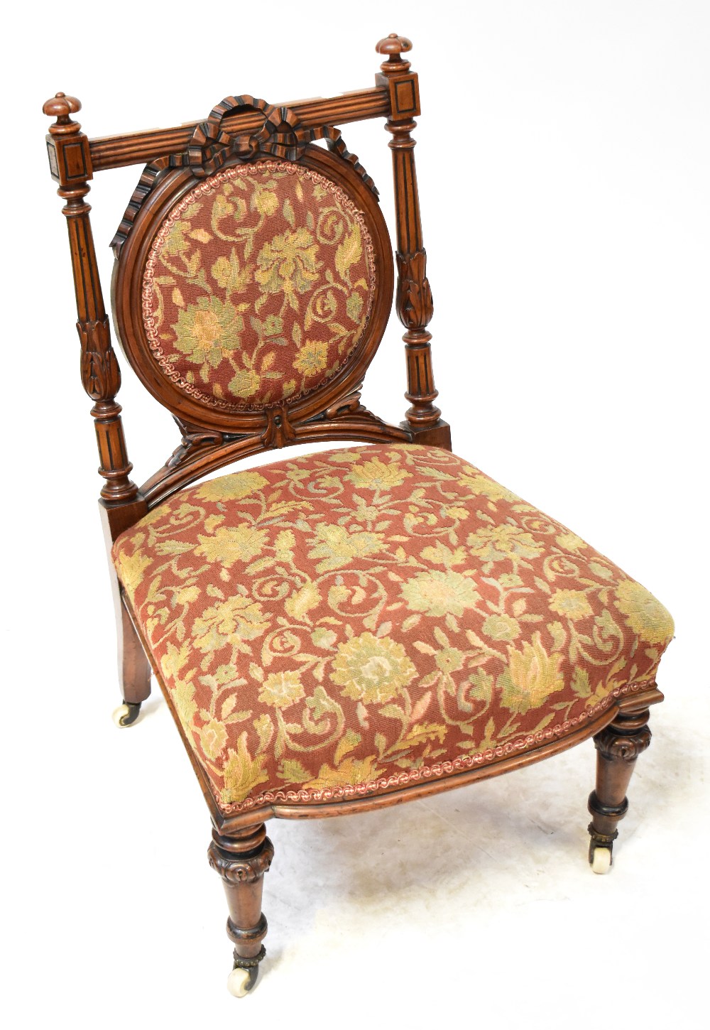 A Victorian walnut nursing chair, circular pad back rest with bow and swag decoration,