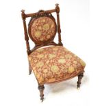 A Victorian walnut nursing chair, circular pad back rest with bow and swag decoration,