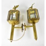 A pair of wall lights in the form of brass coach lights with eagle finials,