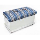 A pale blue painted pine ottoman with upholstered hinged lid, raised on castors, 56 x 90 x 47cm.