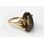 A 9ct gold dress ring with large oval claw set clear brown stone, possibly topaz, on 9ct gold shank,