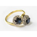 An 18ct gold two-stone sapphire cross-over ring, with two claw set blue sapphires,