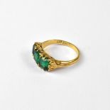 An 18ct gold dress ring set with three graduated green glass stones,