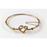 A vintage 9ct gold knotted heart tubular hinged bracelet, with small 9ct gold safety chain,