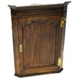 An early 19th century oak wall-hanging corner cabinet with two interior shelves,
