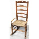 A 19th century oak provincial Lancashire ladder back rocking chair, with rush seat,