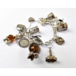 A sterling silver charm bracelet with various silver charms to include birdcage, well, teddy bear,