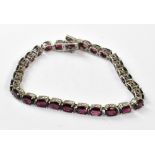 A silver articulated bracelet set with twenty-eight purple-red stones.