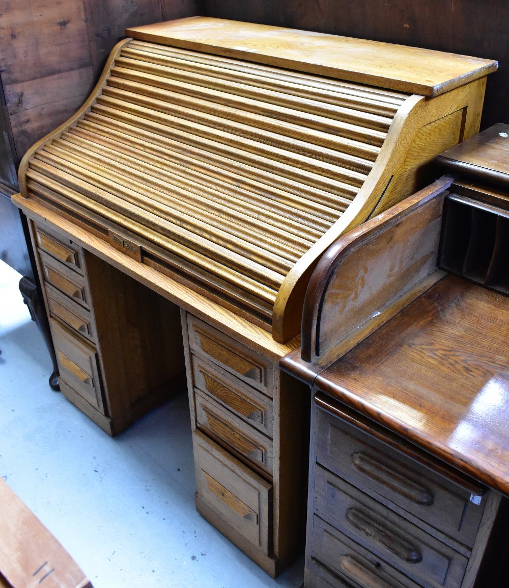 An early 20th century oak roll-top desk, the upper tambour section above twin pedestals,