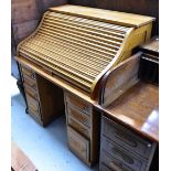 An early 20th century oak roll-top desk, the upper tambour section above twin pedestals,