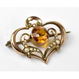 An Art Nouveau style 9ct gold brooch with central amber-coloured cut bezel set stone,