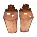 A pair of 19th century walnut wall mounted candle boxes, the shaped backs above sloping hinged lids,