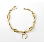 A 9ct gold fancy link bracelet with hoop fastener and an attached horseshoe charm to the centre,