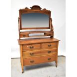 An early 20th century walnut dressing chest, the arched bevelled mirror plate within carved frame,