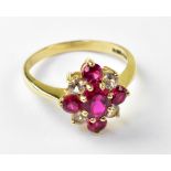 A ruby and white stone cluster ring with central claw set ruby and smaller ruby to top,