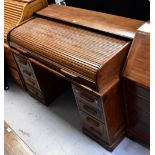 An early 20th century oak roll-top desk, the upper tambour section enclosing a fitted interior,