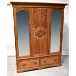 An Edwardian satin walnut triple wardrobe with moulded cornice above carved central panel,