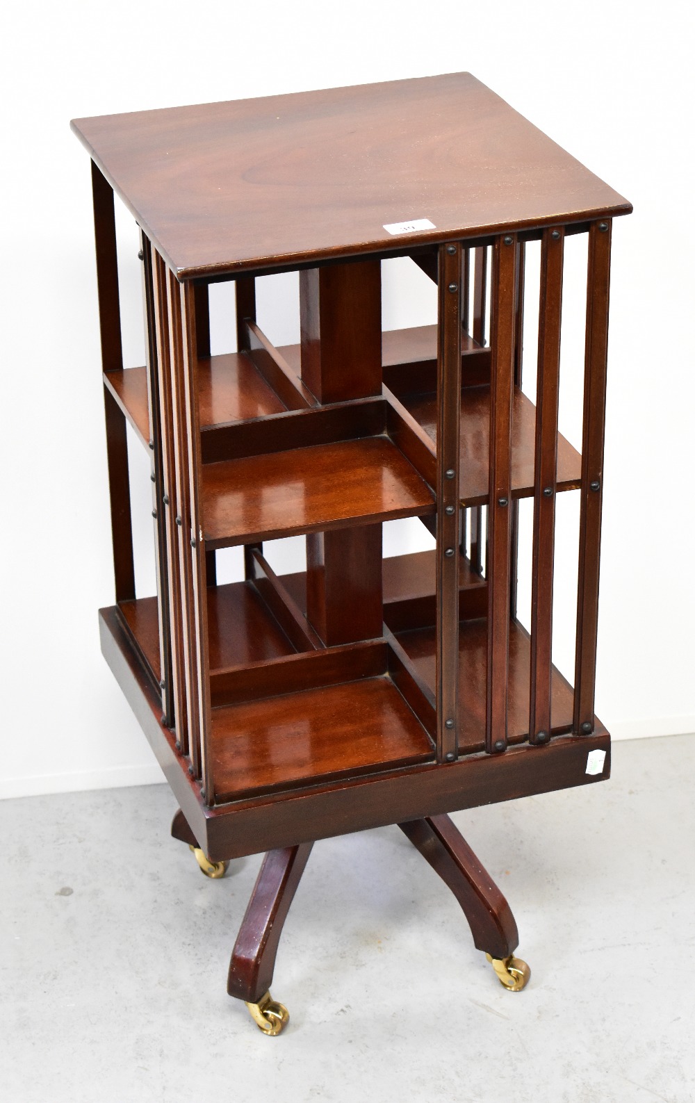 A mahogany revolving bookcase raised on quadripartite base to castors, 61 x 38 x 38cm.