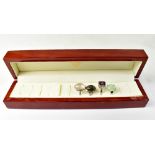 A wooden ring box with four silver ladies' dress rings,